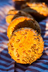 Closeup of sesame seeds encrusted in orange glaze of pumpkin flavor macaron cookies - 541992841