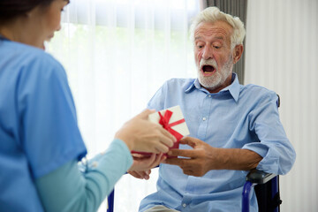 senior man taking a gift box from caregiver for happy birthday