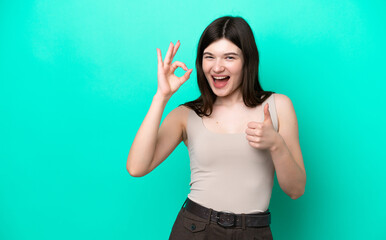 Fototapeta na wymiar Young Russian woman isolated on green background showing ok sign and thumb up gesture