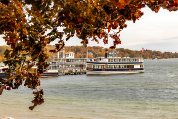 An autumn tree and tour boats at the pier on Lake Geneva, Wisconsin.