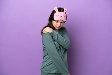 Young Russian woman in pajamas isolated on purple background suffering from pain in shoulder for having made an effort