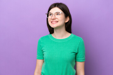 Fototapeta premium Young pretty Russian woman isolated on purple background With glasses with happy expression