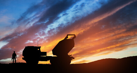 Artillery rocket system are aimed to the sky and soldier at sunset. Multiple launch rocket system....