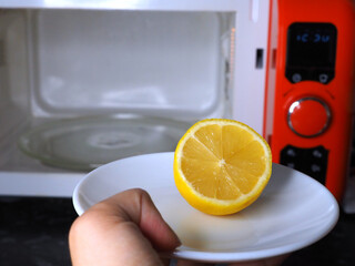 Housewife cleaning microwave oven using lemon