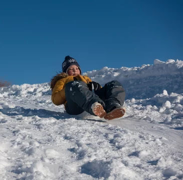 happy boy sliding down snow hill on sled outdoors in winter, sle Stock  Photo