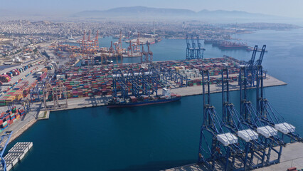 Fototapeta premium Aerial closeup photo of colourful container seaside port and logistics terminal in crane area while loading-unloading to tanker vessel