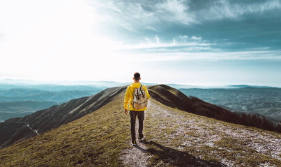 Young man with backpack hiking mountains - Hiker having trekking day out on a sunny day -...