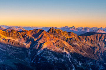 Naklejka premium Alpine mountain peaks illuminated by rising sun