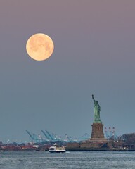 Verticale opname van de volle maan met het Vrijheidsbeeld in New York City
