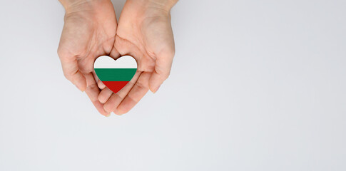 The flag of the Bulgaria in the shape of a heart of arms in female hands. Flat lay, copy space.