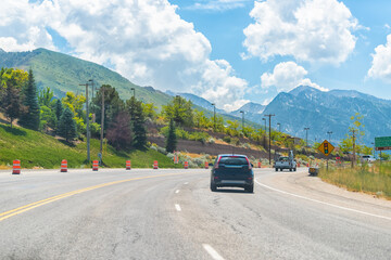 Cars driving on interstate highway road at Park City, Utah ski resort town with Wasatch mountains...