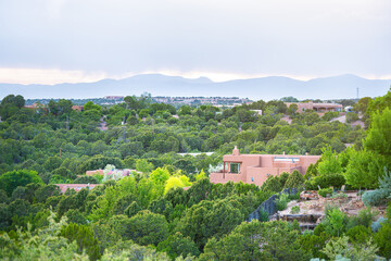 Fototapeta na wymiar Cityscape view in Santa Fe, New Mexico Sangre de Cristo mountains by residential street community, green plants in summer and adobe traditional houses