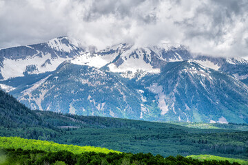 Kebler pass landscape view on snowcapped mountains with snow by aspen spruce pine trees forest wilderness in summer with peak summit