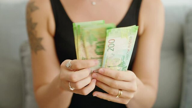 Young woman counting russia 200 ruble banknotes at home