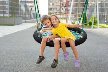 A boy and a girl ride on a swing, a spider web, a nest and have fun.