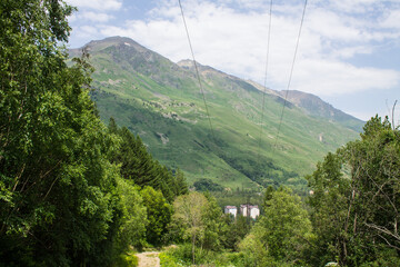 Panoramic view of the village of Cheget with residential buildings among the high slopes of mountains with glaciers on the tops on a sunny summer day in the Elbrus region in the North Caucasus