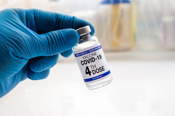 COVID-19 Vaccine Vial for vaccination tagged with 4th dose. doctor with Coronavirus vaccine bottle...