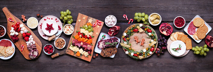 Christmas charcuterie table scene against a dark wood banner background. Assorted cheese and meat...