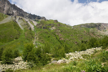 Pastoral mountain landscape with peaks with glaciers and a bright alpine meadow with green grass in a valley near Elbrus in the North Caucasus