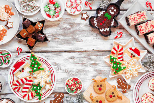 Cute Christmas sweets and cookie frame. Overhead view on a rustic white wood background with copy space. Fun holiday baking concept.