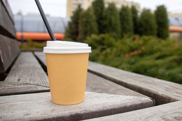 Paper glass with drink on a wooden bench