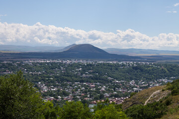 Fototapeta na wymiar Panoramic view of Pyatigorsk in the Stavropol Territory with tasks among green trees and a mountain against the background of a dramatic cloudy sky on a summer day