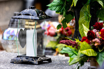 Candles and flowers on graves in the cemetery during the All Saint's Day. Taken during the day,...