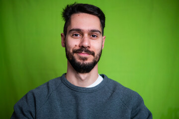Young man with casual clothes, posing on green background