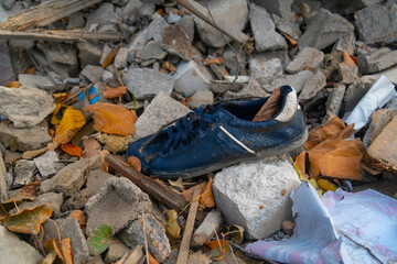 War in Ukraine. 2022 Russian invasion of Ukraine. A dark blue shoe lies near the ruined house....