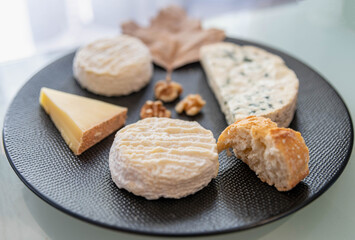 Plateau de fromages avec une feuille de platane séché et un assortiment avec des morceaux de...