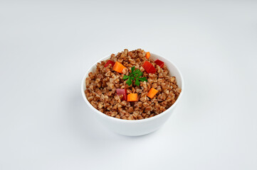 buckwheat porridge in a white plate with vegetables on a plate, white background