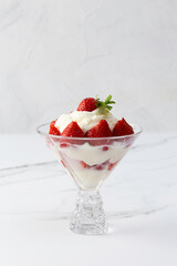 whipped cream with strawberries in a bowl on a light background