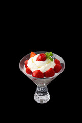 whipped cream with strawberries in a bowl on a black background