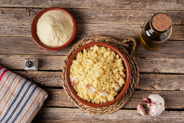 Rustic dish with crumbs, traditional Spanish food, along with the necessary ingredients for its preparation, flour, oil, garlic and salt. Top view.