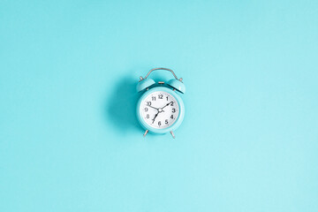 Blue alarm clock on pastel blue background. Flat lay, top view, copy space