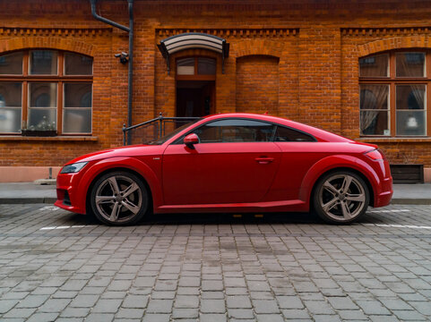 Lodz, Poland - February 22 2020 Red Audi TT in front of old small red brick building