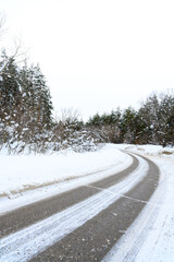 Snowy winter road in a mountain forest.