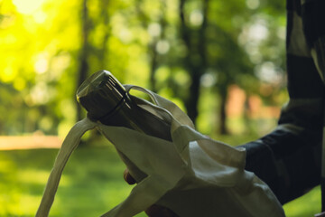 Close-up of Unrecognizable female hand holding Water bottle from eco bag. Reusable steel thermo...