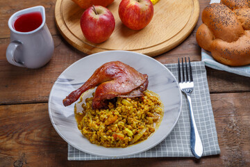 Rosh Hashanah next to fruit wine and challah on the table and candles next to a duck's leg and spelt in a plate.