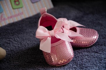 Closeup shot of pink shiny baby shoes on a carpet