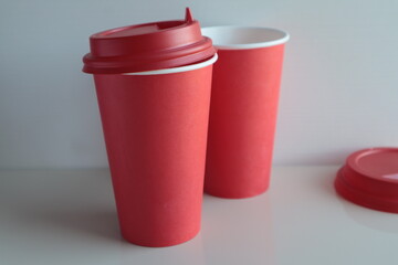 Red paper disposable cups stand on a light surface.
