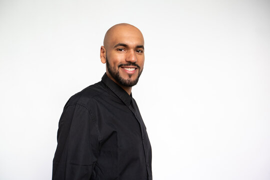 Portrait of happy young businessman looking at camera and smiling. Positive bearded man wearing black shirt posing against white background. Successful businessman concept