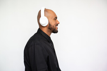 Side view of happy young man listening to music against white background. Bearded businessman wearing black shirt looking away and smiling. Music and leisure concept - Powered by Adobe