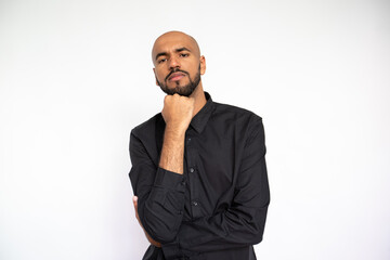 Portrait of confident businessman looking at camera. Bearded man wearing black shirt posing with hand on chin against white background. Planning concept