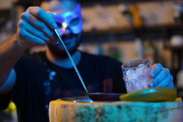 a man's hand ladles mulled wine into a glass with ice from a bowl made of pumpkin