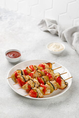 Baked Chicken kebab meat with vegetables, sweet pepper, zucchini on skewers on white plate and grey background. Dinner diet concept.