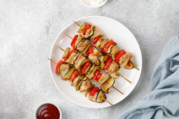 Baked roasted cooked Chicken meat with vegetables, sweet pepper, zucchini, kebab on skewers on white plate and grey background. Dinner diet concept.