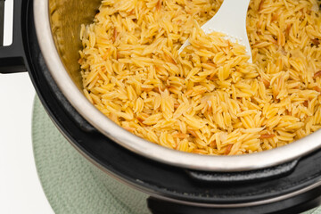 Pasta cooked in Instant Pot. Delicious orzo pasta close up in a pot on white background with copy space