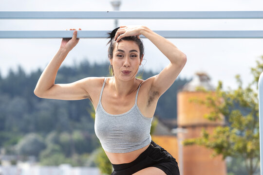 Pretty Asian woman with underarm hair wearing a grey tank top outside on a sunny day