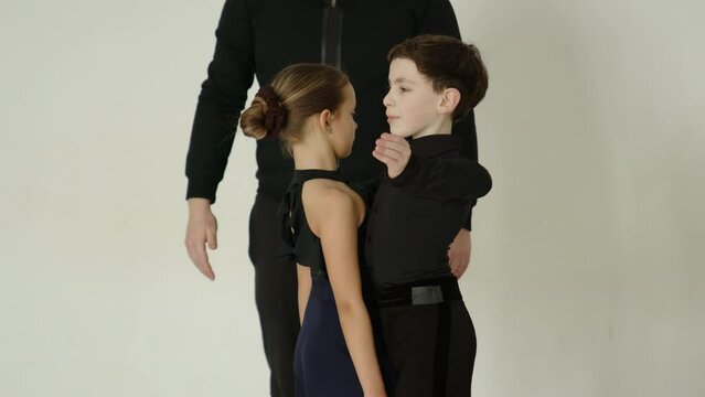 Children study ballroom dancing with a choreographer on a dancing lesson. Boy and girl learns the dancing steps in a choreography class. High quality 4k footage